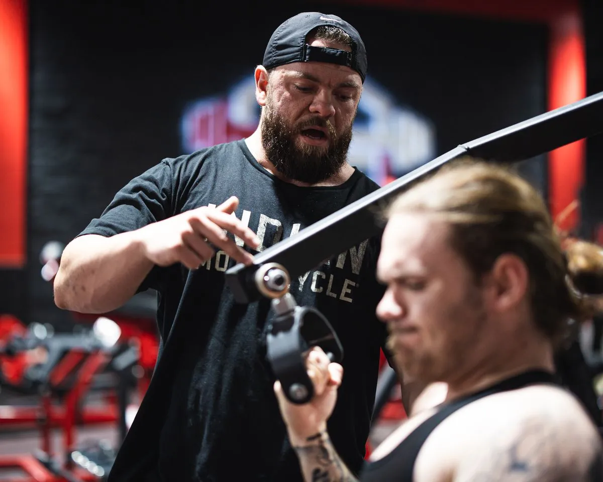 A personal trainer guiding a member through a strength exercise at the gym