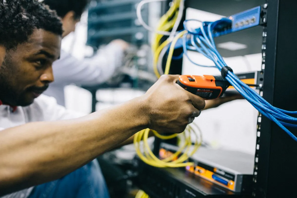 An IT technician repairing equipment beside network cables