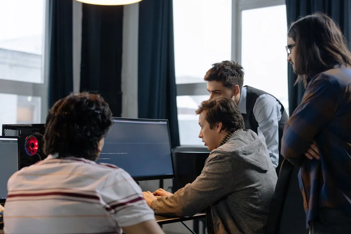 Software developers collaborating around a computer in a bright office